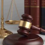 Gavel and scales of justice in front of law books.