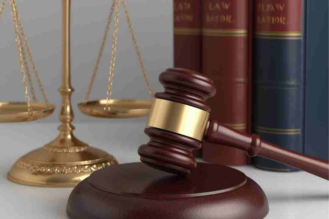 Gavel and scales of justice in front of law books.